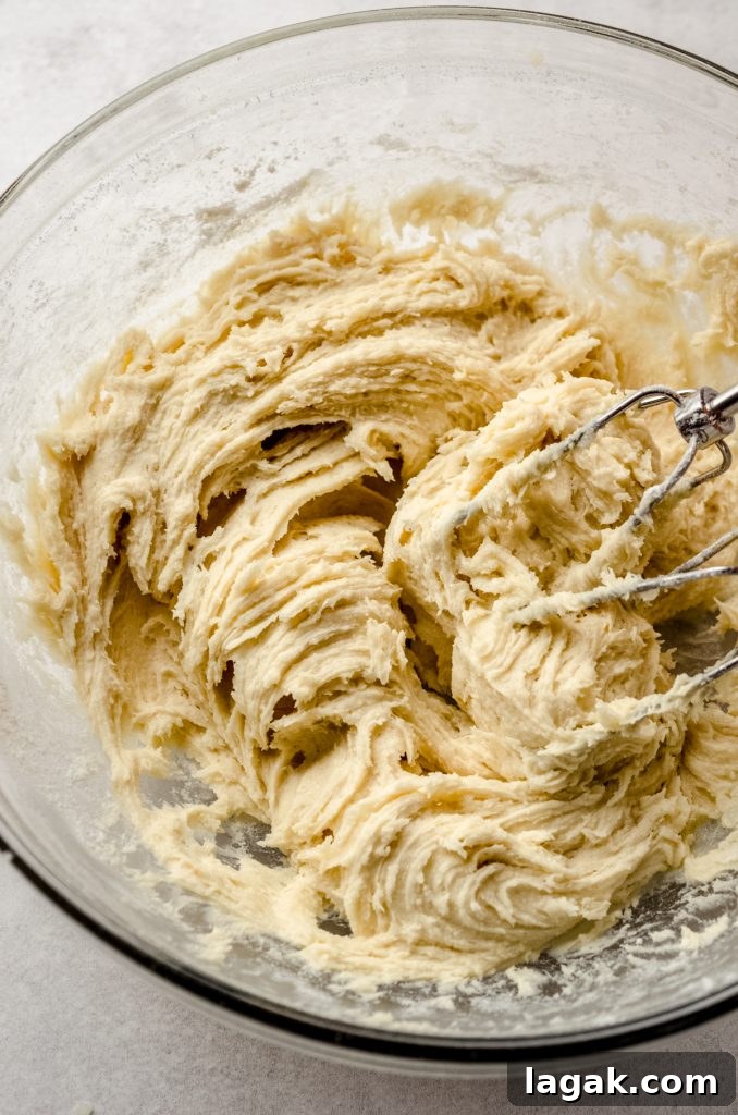 Cream Cheese Drop Cookies – Soft, Sugar Coated Treats 7 A bowl of cream cheese sugar cookie dough with electric beaters.