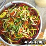 Bird's eye view of a bowl of spiralized beet, carrots and zucchini noodles with peanut sauce