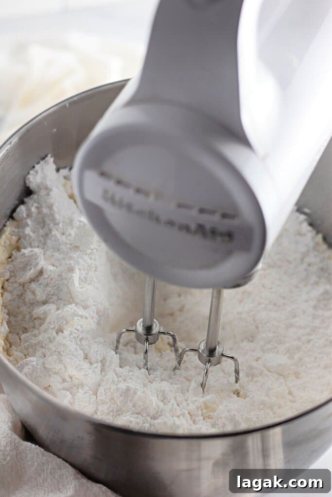 Moist Maraschino Cherry Cake Recipe with Cherry Glaze 9 Butter and powdered sugar are being mixed with a hand mixer.
