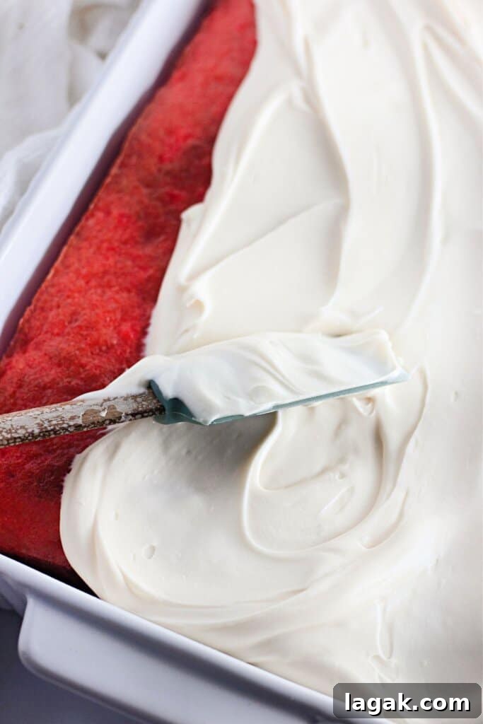 Moist Maraschino Cherry Cake Recipe with Cherry Glaze 10 Frosting being spread on top of cake.