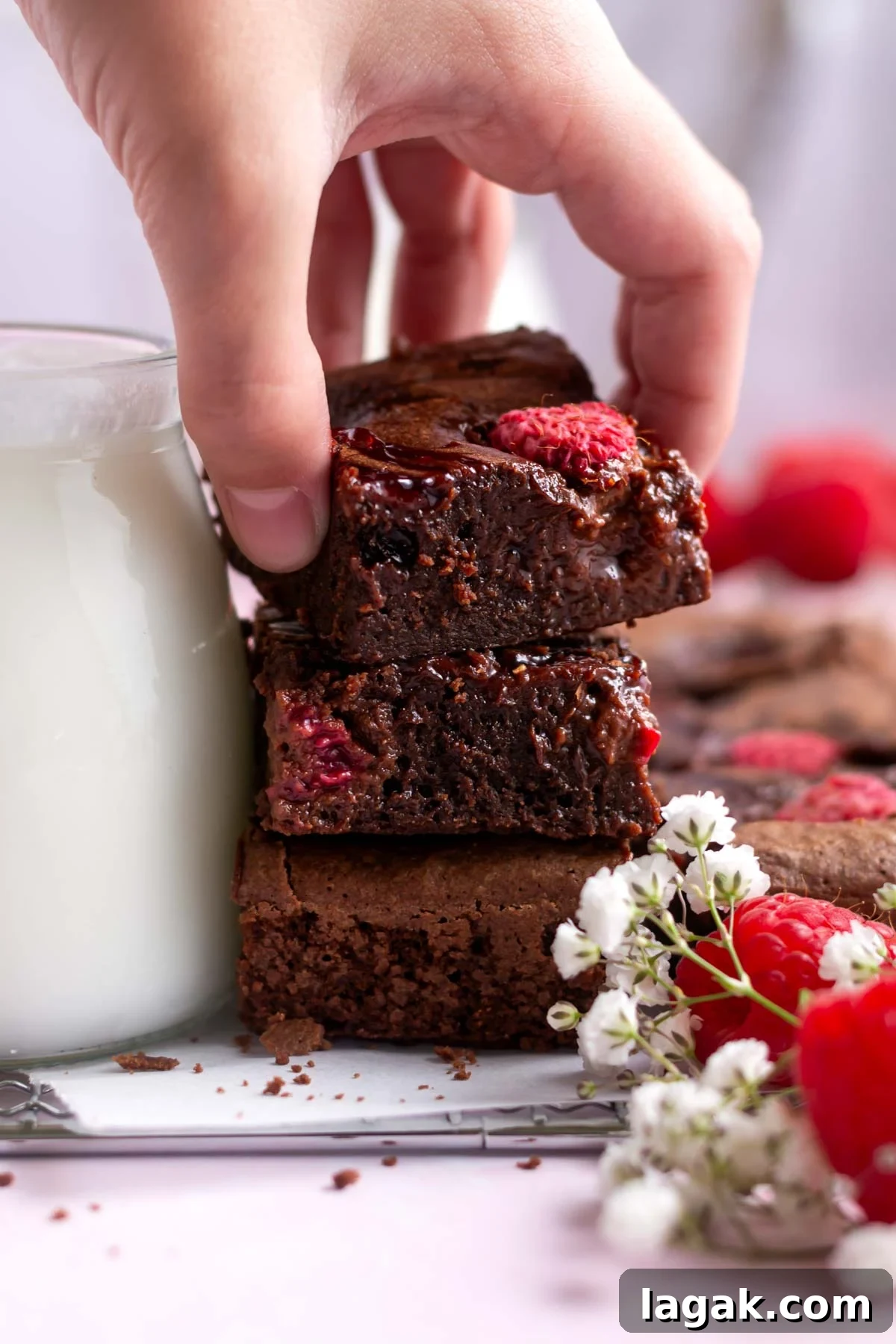 hand grabbing a raspberry brownie from a stack