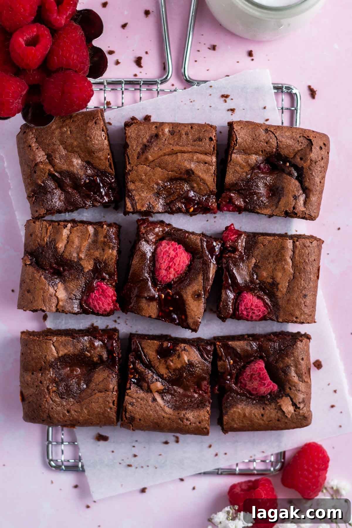 raspberry brownies on a parchment lined cooling rack with fresh raspberries and milk