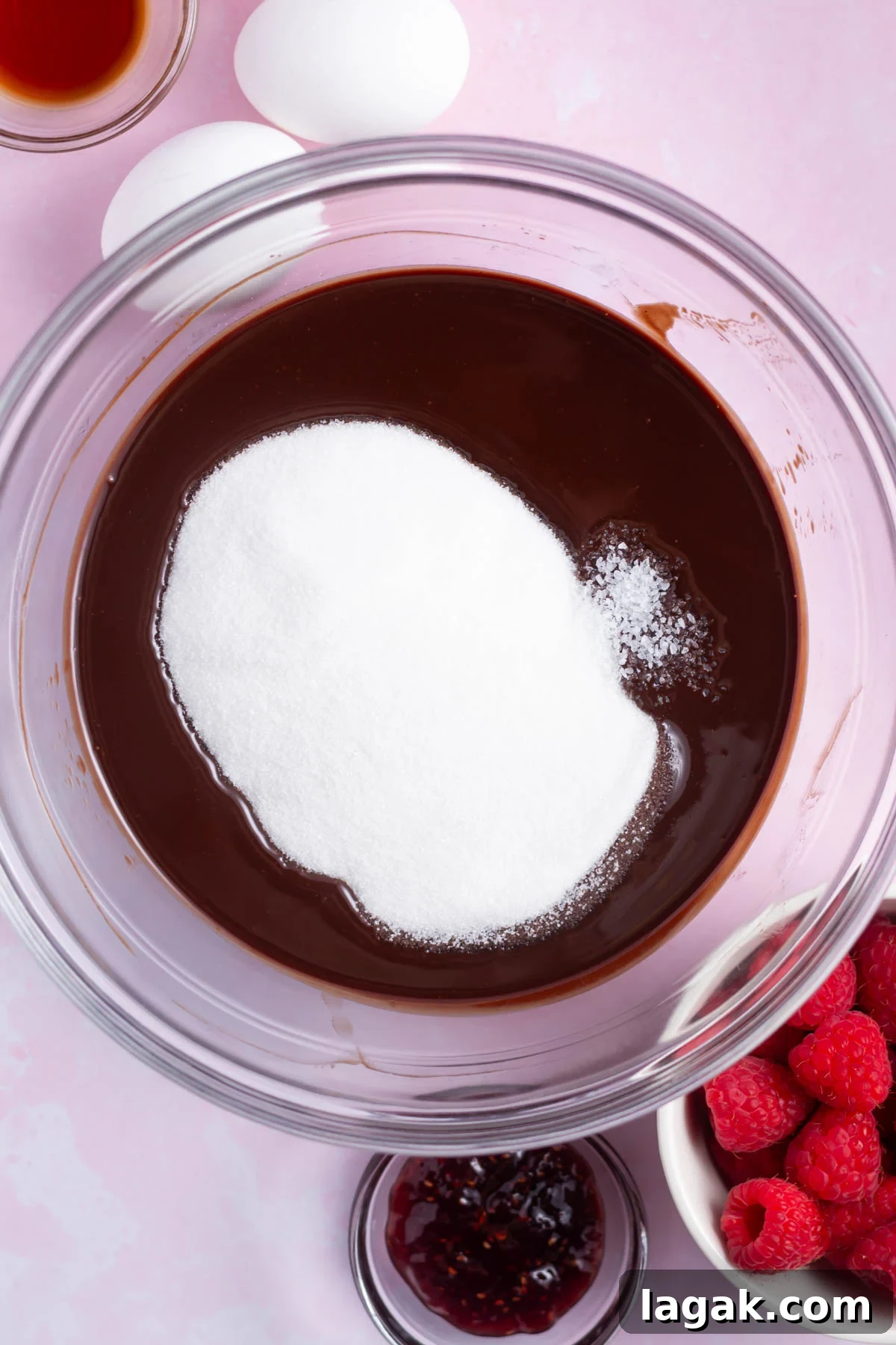 sugar added to melted chocolate and butter in a bowl