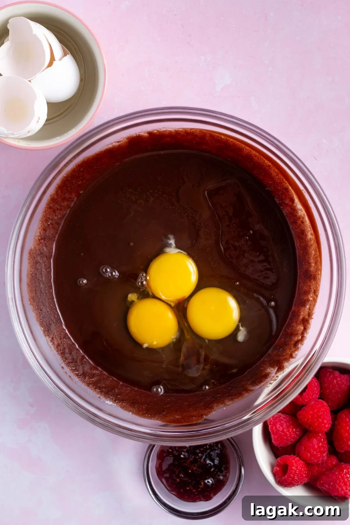 three eggs added to brownie ingredients in a bowl