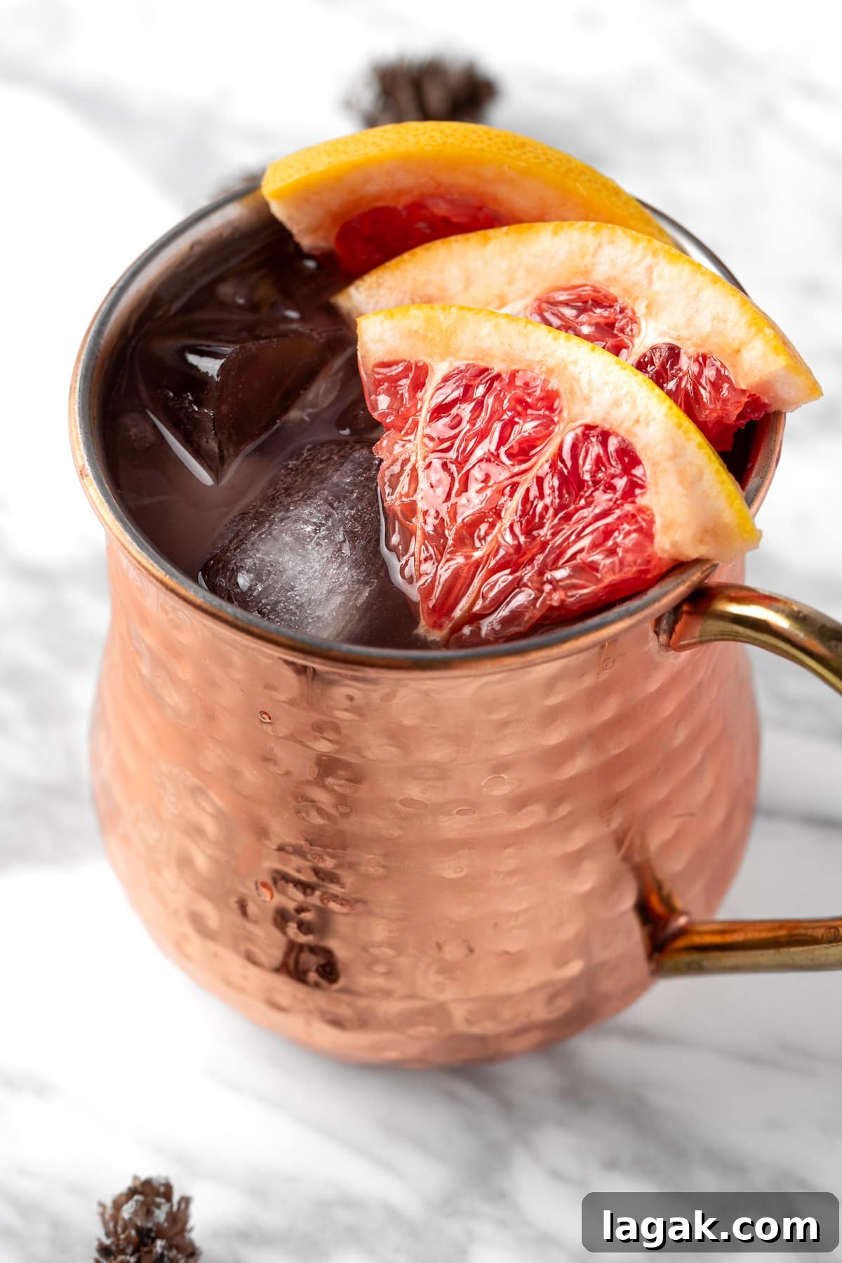 A grapefruit moscow mule in a copper mug served with grapefruit slices.
