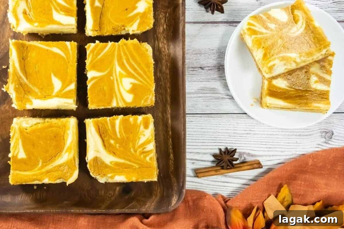 27 Cozy Fall Desserts That Taste Like Brown Sugar, Butter, and Memories 16 Six pumpkin cheesecake bars with a marbled pattern on a wooden tray, with two bars on a white plate beside cinnamon sticks and star anise on a white wooden table.