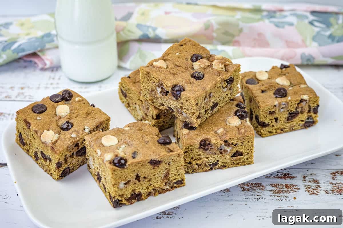 27 Cozy Fall Desserts That Taste Like Brown Sugar, Butter, and Memories 23 A white rectangular plate with pieces of pumpkin blondies.