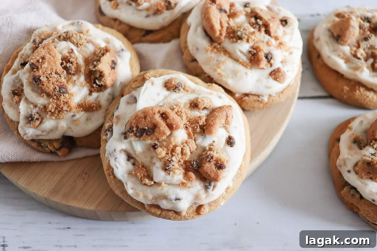 27 Cozy Fall Desserts That Taste Like Brown Sugar, Butter, and Memories 26 Frosted chocolate chip cookie cookies on a wooden cutting board.
