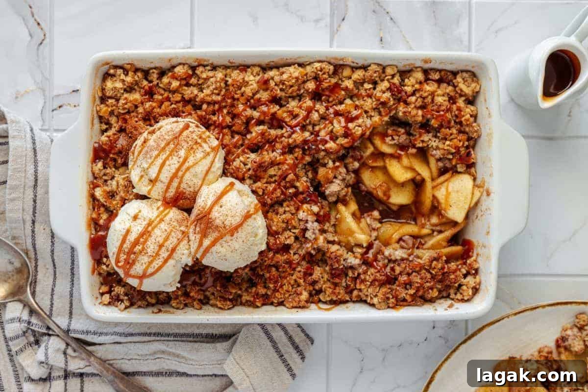 27 Cozy Fall Desserts That Taste Like Brown Sugar, Butter, and Memories 4 An Apple Crisp with Vanilla Ice Cream, served in a rectangular dish, topped with two scoops of vanilla ice cream and a caramel drizzle, accompanied by a portion on a plate beside it.