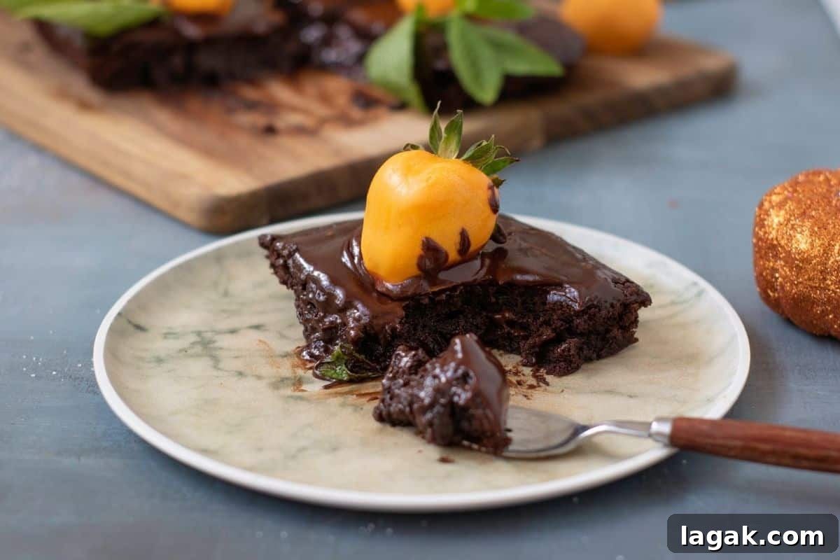 27 Cozy Fall Desserts That Taste Like Brown Sugar, Butter, and Memories 6 A piece of Pumpkin Patch Brownie Cake. sits on a plate with a fork. More cake is visible in the background on a wooden board.