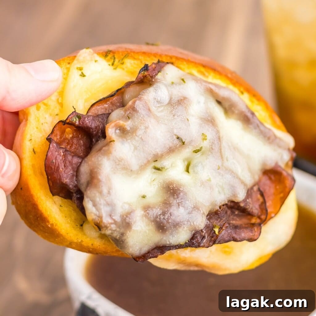 Garlic Bread French Dip Sandwiches: Savory Dipping Recipe 2 Close-up of a garlic bread French dip sandwich topped with melted provolone cheese and roast beef, ready to dip in au jus.