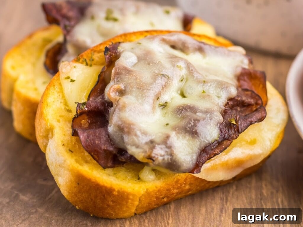 Garlic Bread French Dip Sandwiches: Savory Dipping Recipe 6 Two cheesy garlic Texas toast French dip sandwiches with provolone cheese and roast beef on a wooden board.
