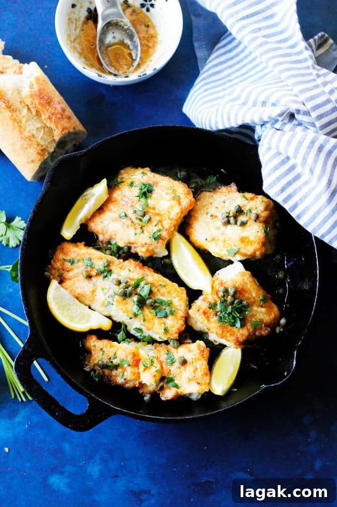 Pan Fried Cod with Meuniere Sauce served with bread Fried Cod in a skillet with brown butter lemon sauce on a side and bread