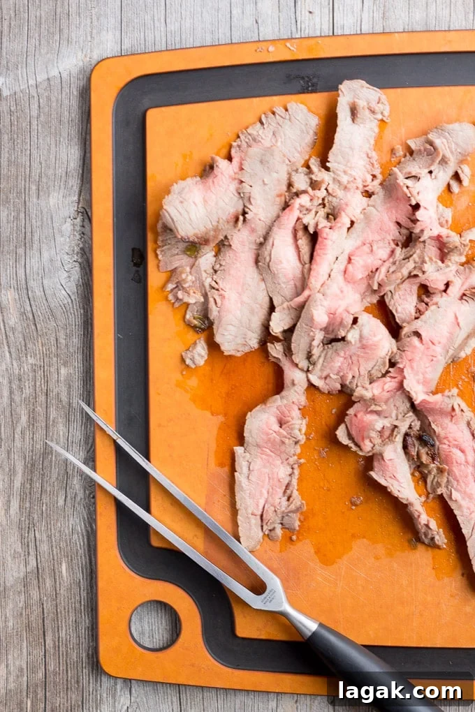Asian-Inspired Gluten-Free Steak Marinade Recipe for Bold Flavor 6 Shaved gluten free flank steak on a brown cutting board with a serving fork.