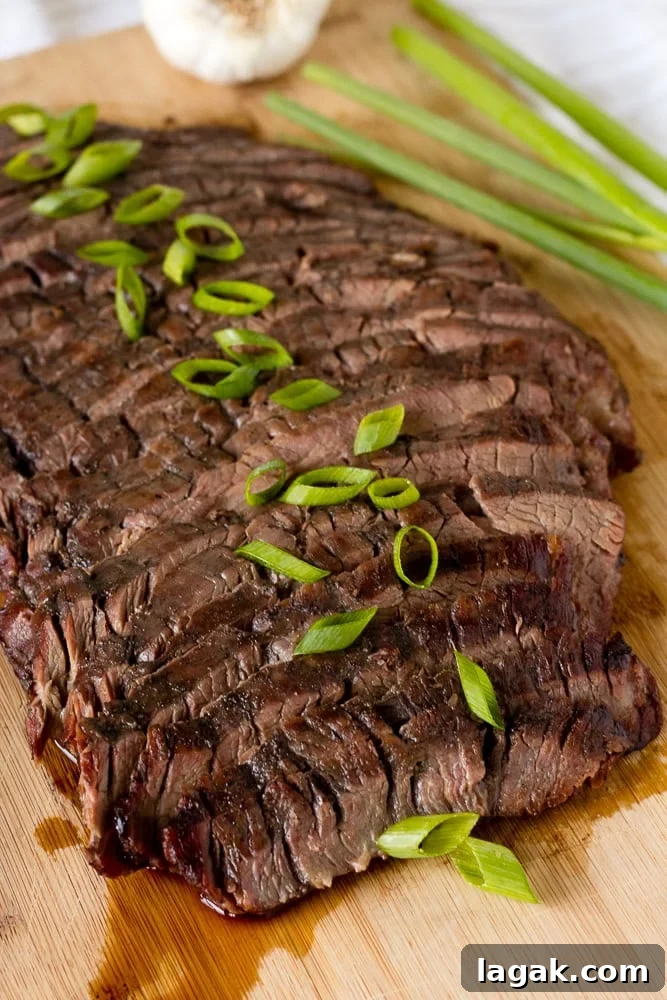 Asian-Inspired Gluten-Free Steak Marinade Recipe for Bold Flavor 7 Close up shot of sliced Asian flank steak with green onions on top of it, all on a wooden cutting board.