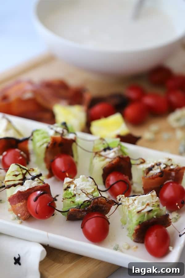 A stray of Wedge Salad Kabobs topped with balsamic glaze on a serving platter.  A bowl of dressing and other ingredients are in the background.