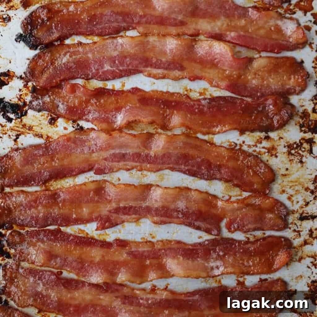 Candied bacon strips cooked and resting on a sheet tray.