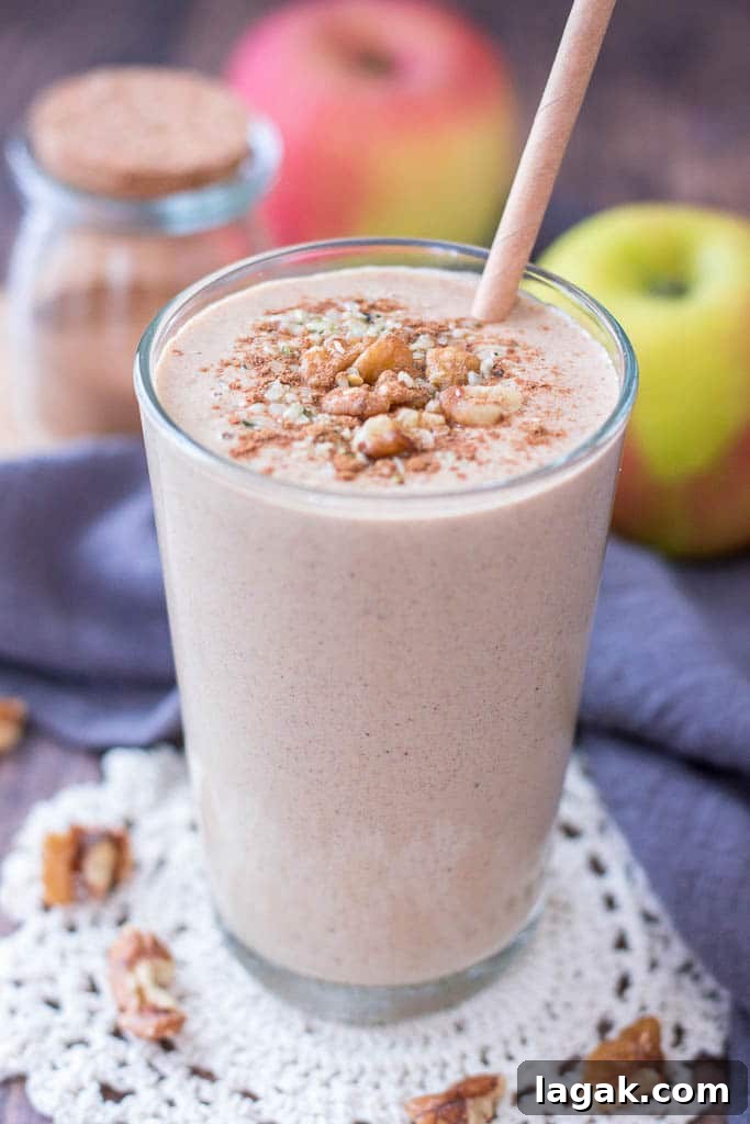 Apple Pie Smoothie topped with walnuts cinnamon and hemp seeds served in a glass with a straw
