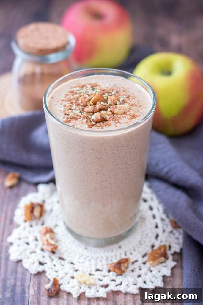 Apple Pie Smoothie topped with walnuts cinnamon and hemp seeds served in a glass with a straw
