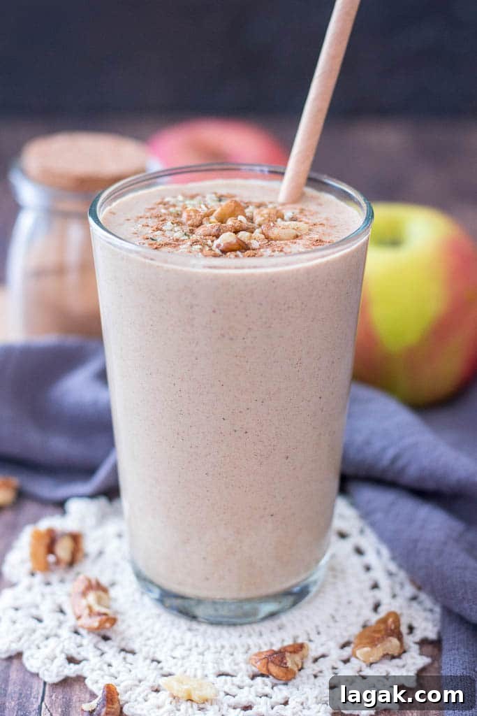Healthy Apple Pie Smoothie topped with walnuts cinnamon and hemp seeds served in a glass with a straw