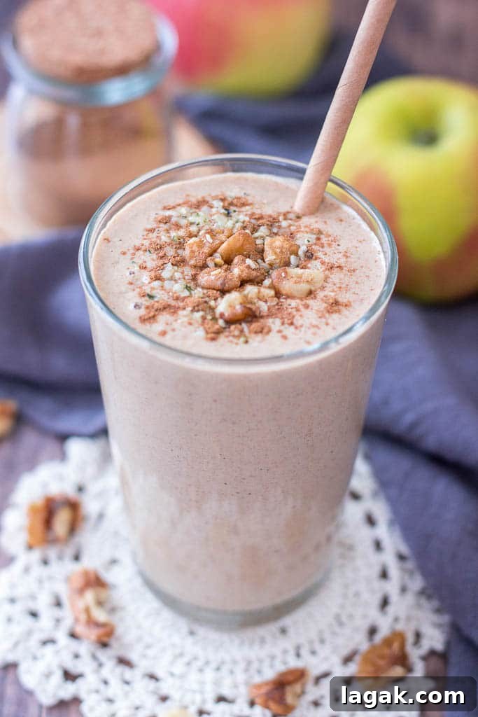 Healthy Apple Pie Smoothie topped with walnuts cinnamon and hemp seeds served in a glass with a straw