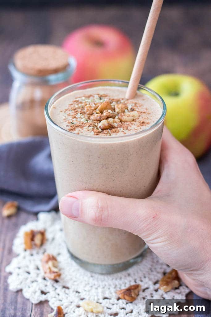 Apple Pie Smoothie topped with walnuts cinnamon and hemp seeds served in a glass with a straw