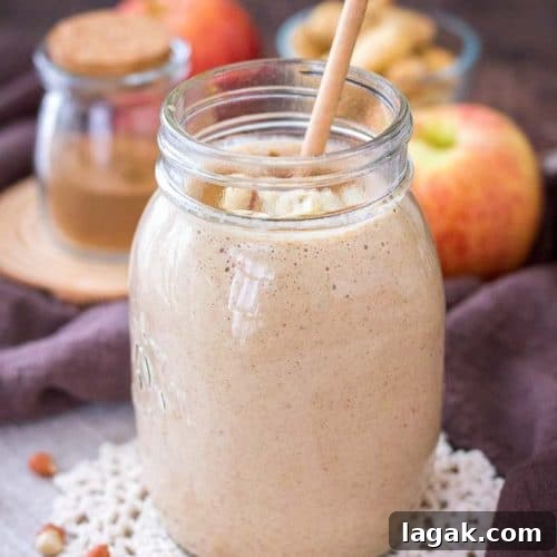 Apple Peanut Butter Smoothie served with a straw in a glass jar topped with creamy peanut butter and crushed peanuts