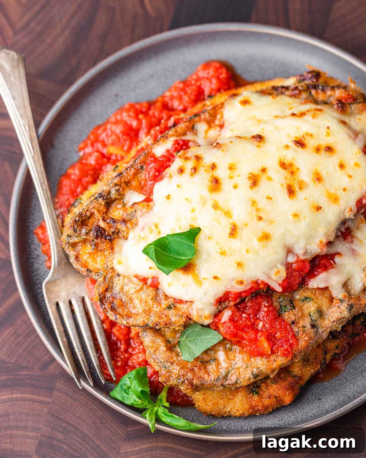 Chicken and Eggplant Parmesan Recipe: Crispy Baked Italian Casserole 2 Chicken eggplant parmesan in grey plate on wood cutting board.