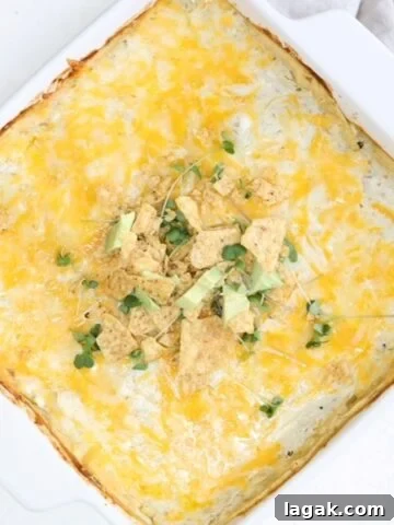 A layered enchilada bake topped in a square white baking dish.