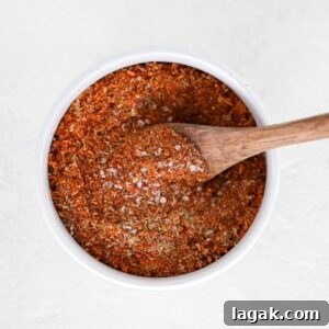 Homemade taco seasoning in a small white bowl with a wooden spoon.