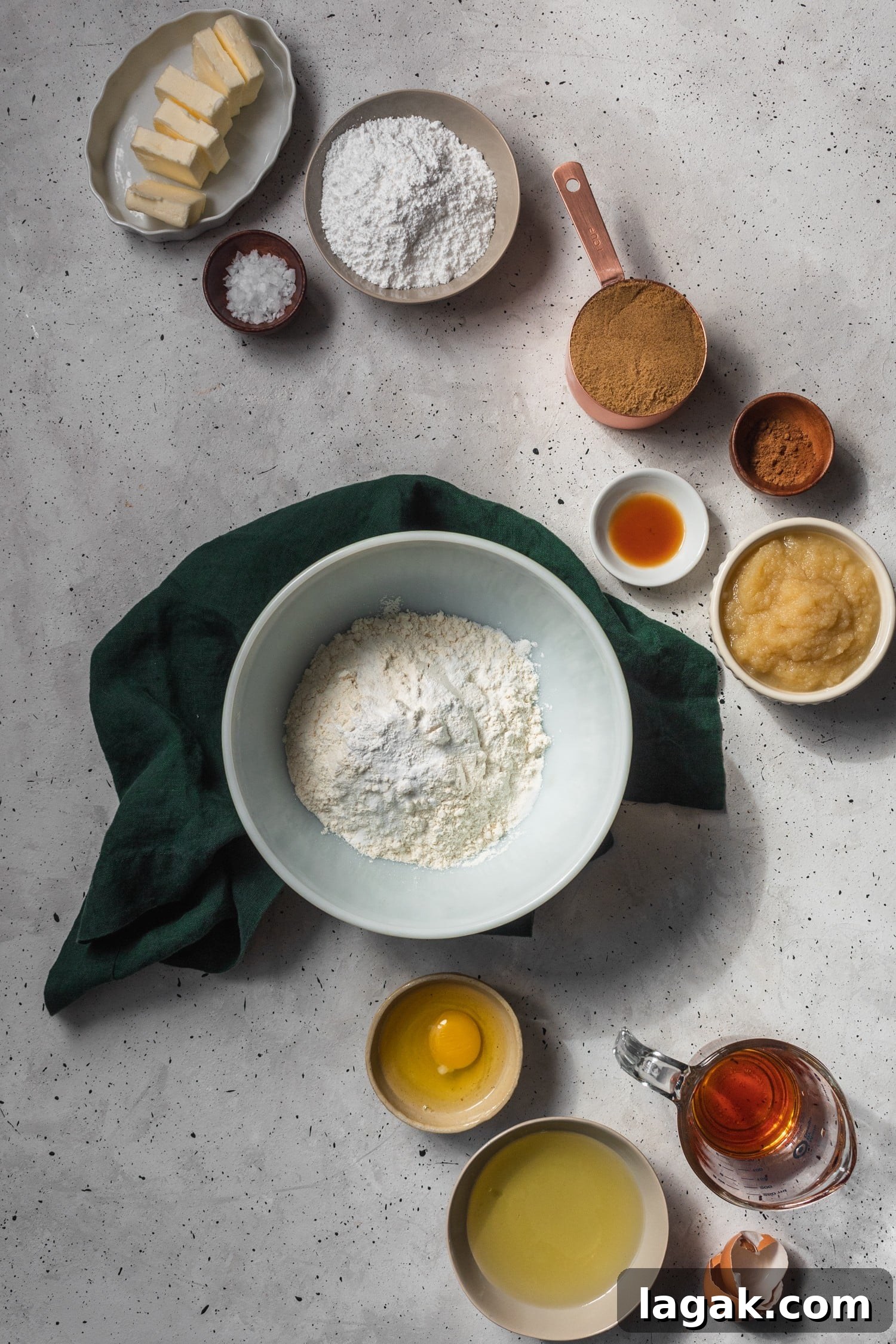An overhead shot of apple cider whoopie pies ingredients in different white and tan bowls on a grey background.