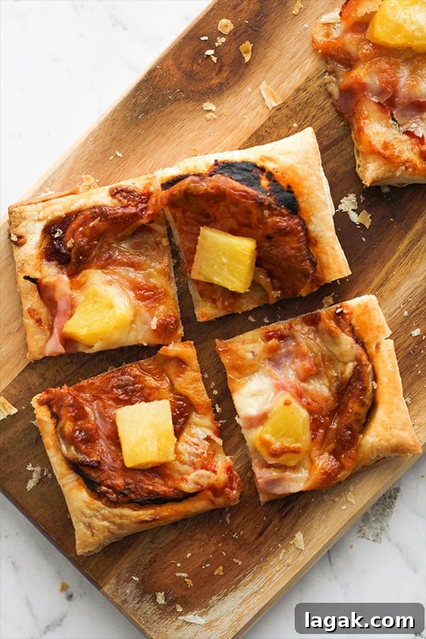 Crispy Puff Pastry Pizza Recipe — Quick Homemade Pizzas 4 slices of Hawaiian pizza on a wooden serving board.