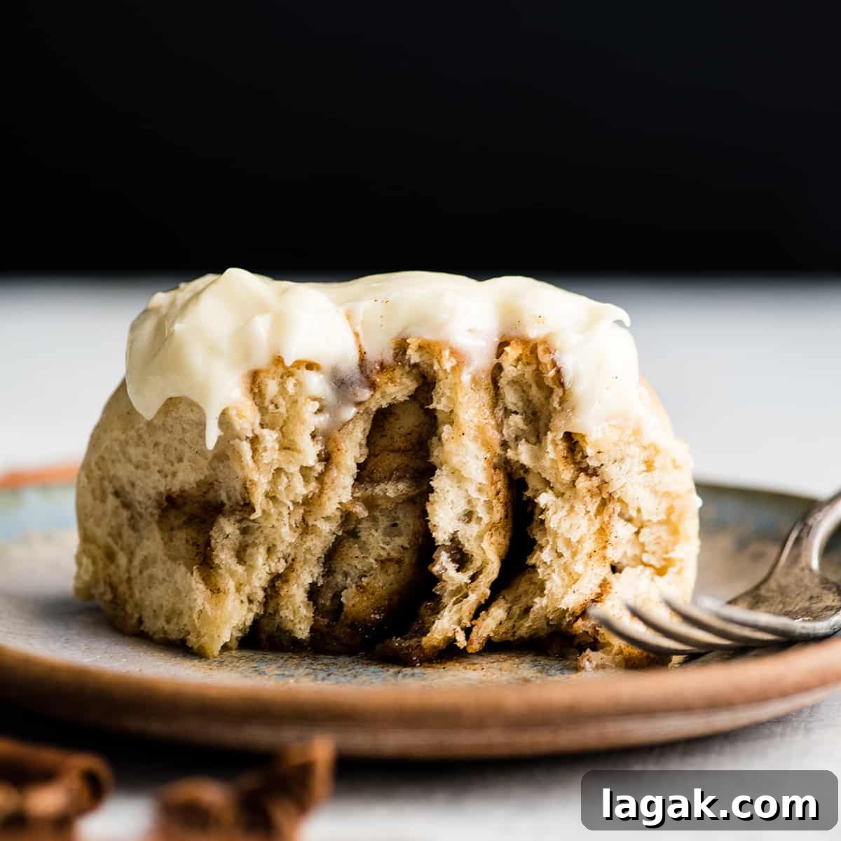 Best Homemade Cinnamon Rolls front photo of a cinnamon roll on a plate with a bite taken out