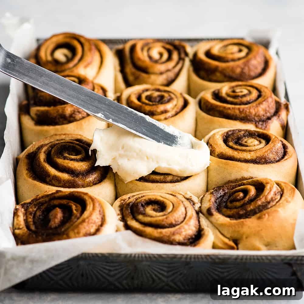 Frost Rolls front view of cinnamon rolls being frosted with cream cheese frosting