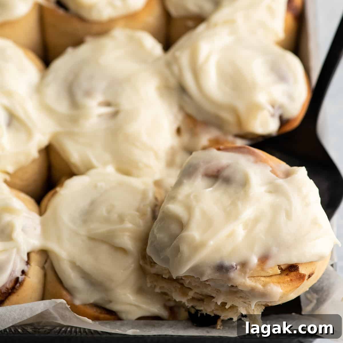 Cinnamon Roll Recipe That Beats Cinnabon: Gooey Overnight Rolls 3 a cinnamon roll being lifted out of a baking pan with a pie server