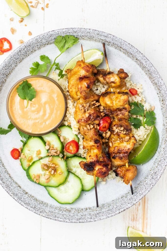 Thai Chicken Satay Recipe: Grilled Skewers with Peanut Sauce 2 A plate with cauliflower rice, cucumber salad, and 2 chicken satay skewers.