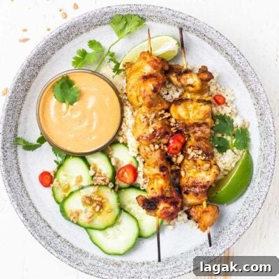 Thai Chicken Satay Recipe: Grilled Skewers with Peanut Sauce 9 A plate showing 2 chicken satay skewers with cauliflower rice and lime.