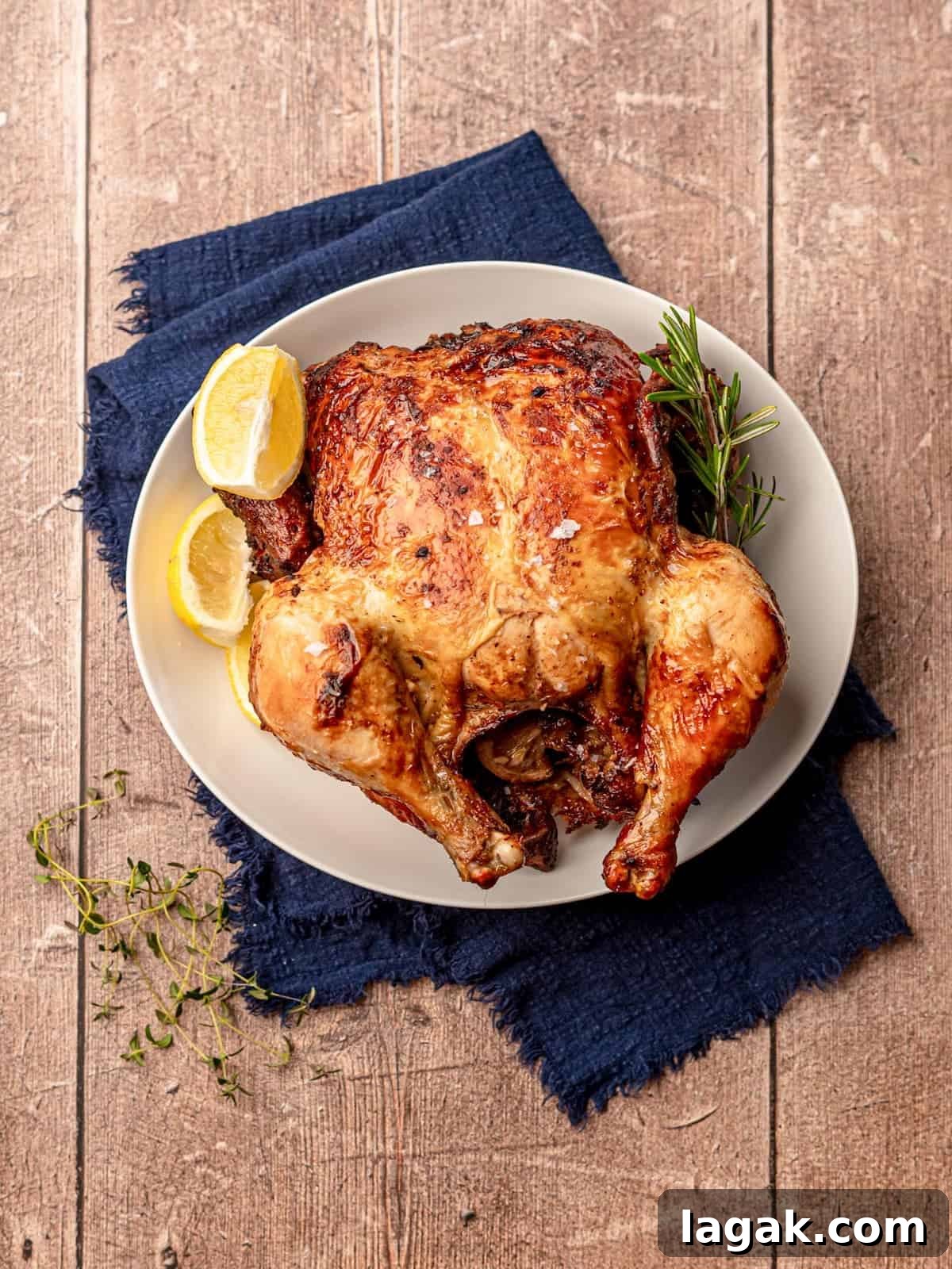 Cooked whole chicken on a plate that is on a blue napkin.