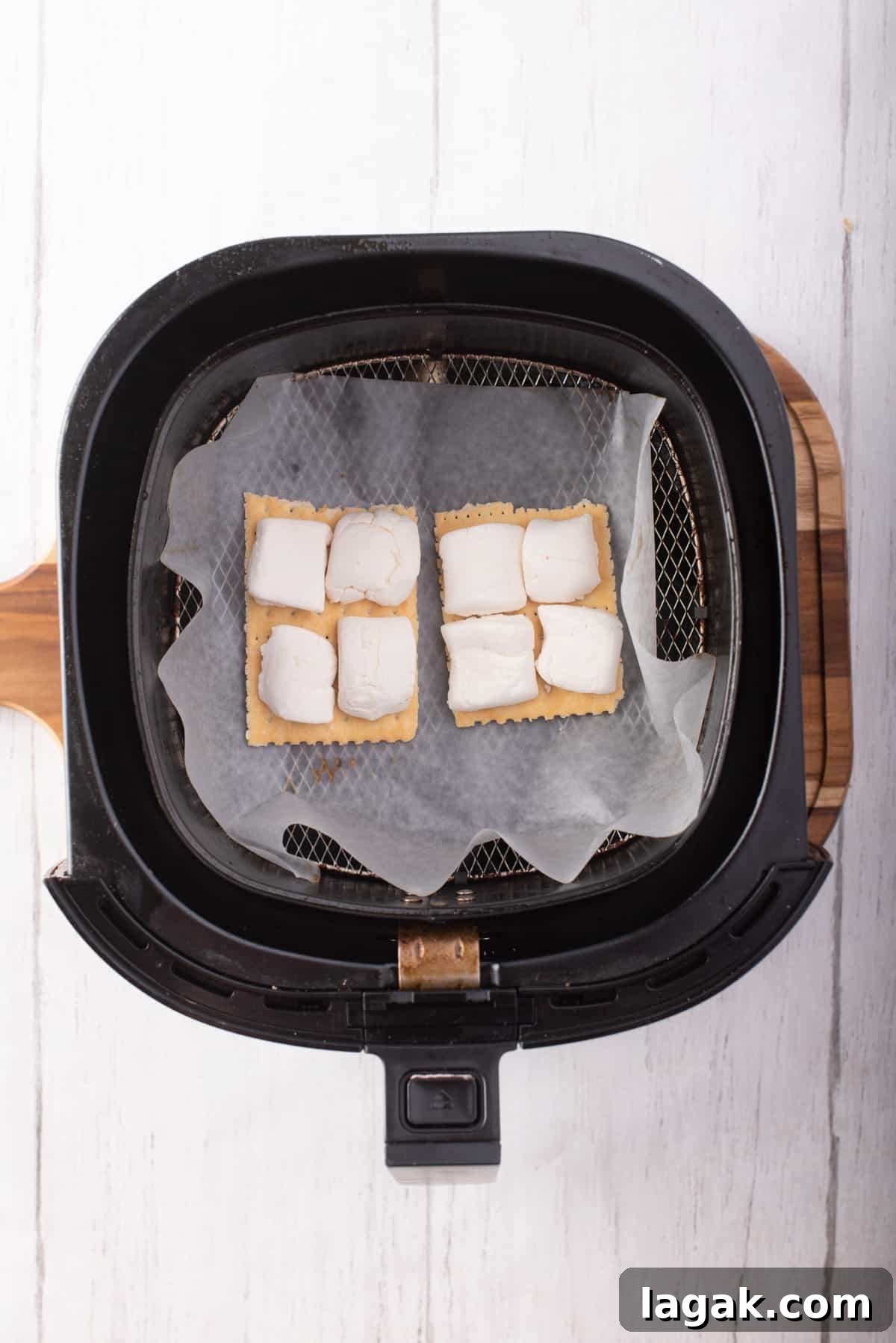 Air Fryer S'mores: Quick Indoor Campfire Dessert Recipe 5 Overhead view of two Graham crackers with marshmallows cut in half on top, placed on the air fryer basket.