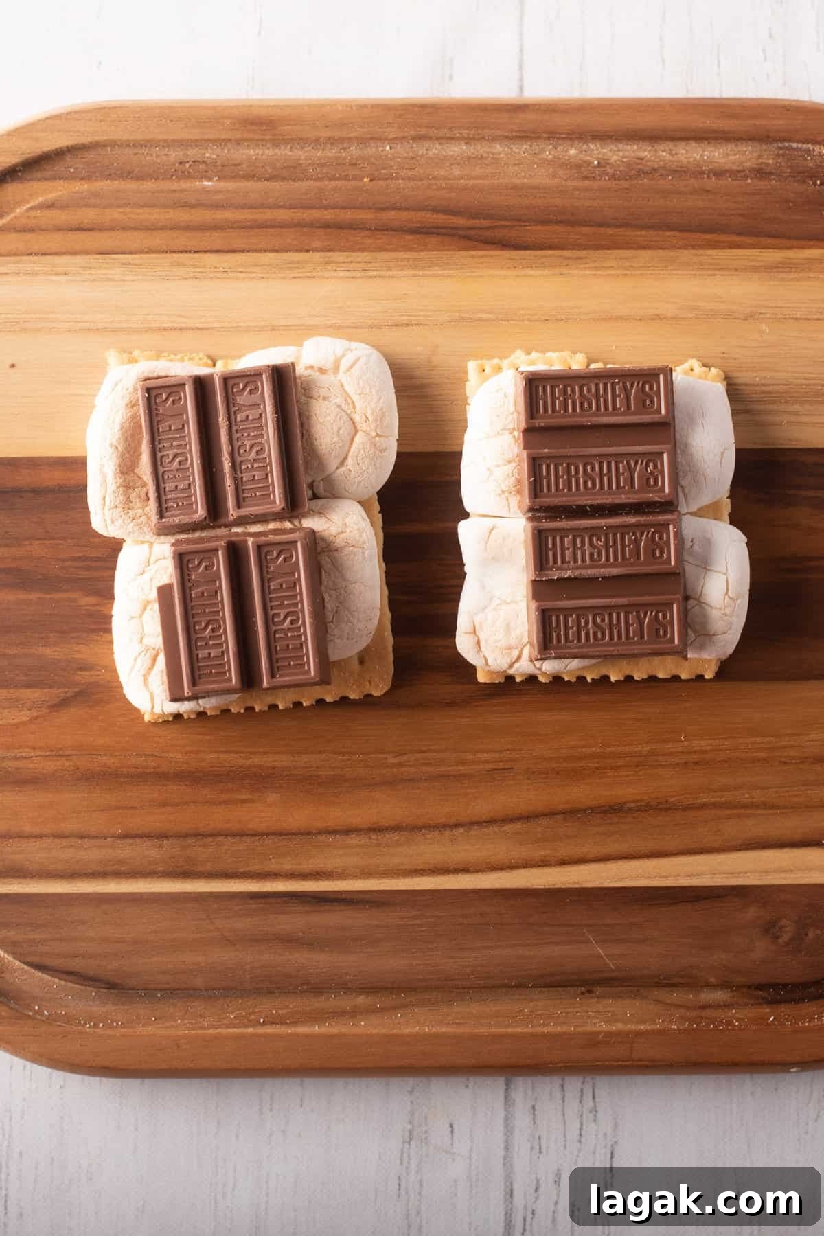 Air Fryer S'mores: Quick Indoor Campfire Dessert Recipe 6 Overhead view of two graham crackers with marshmallows and chocolate pieces on top, placed above a wooden board.