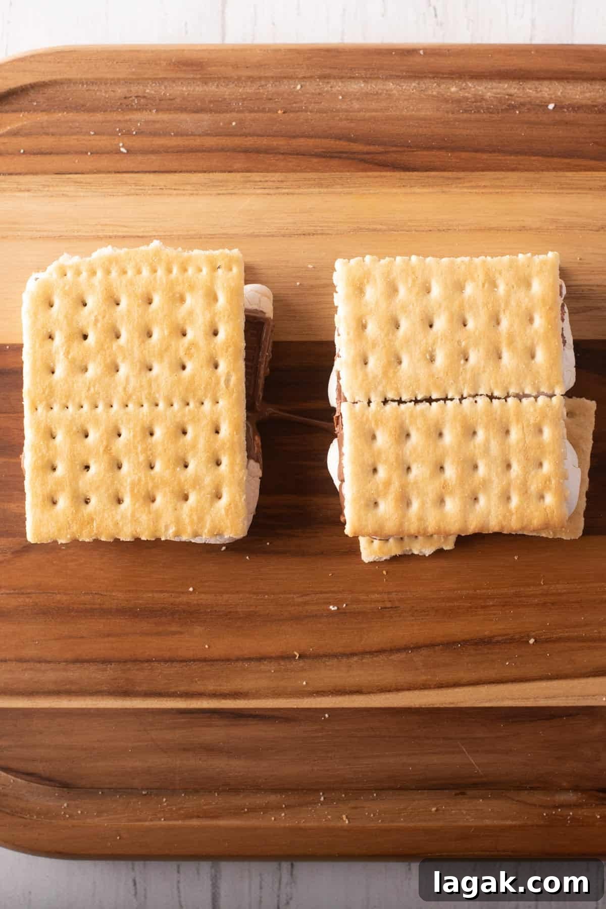 Air Fryer S'mores: Quick Indoor Campfire Dessert Recipe 7 Overhead view of two Graham crackers with chocolate and marshmallow filling placed above a wooden board.