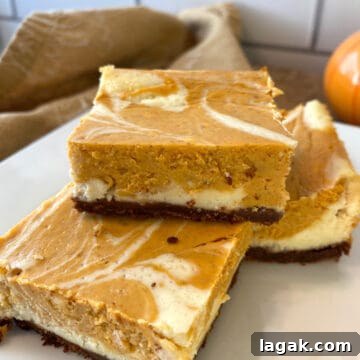 Top Apple and Pumpkin Desserts: 15 Fall Recipes to Try 12 Three pumpkin cheesecake bars stacked on a plate.
