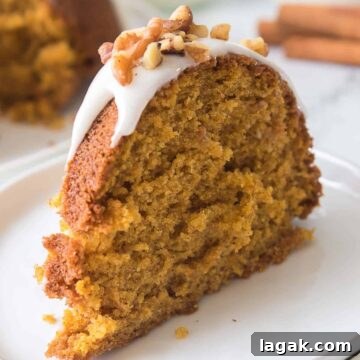 Top Apple and Pumpkin Desserts: 15 Fall Recipes to Try 13 A slice of pumpkin cake on a plate with frosting and nuts.