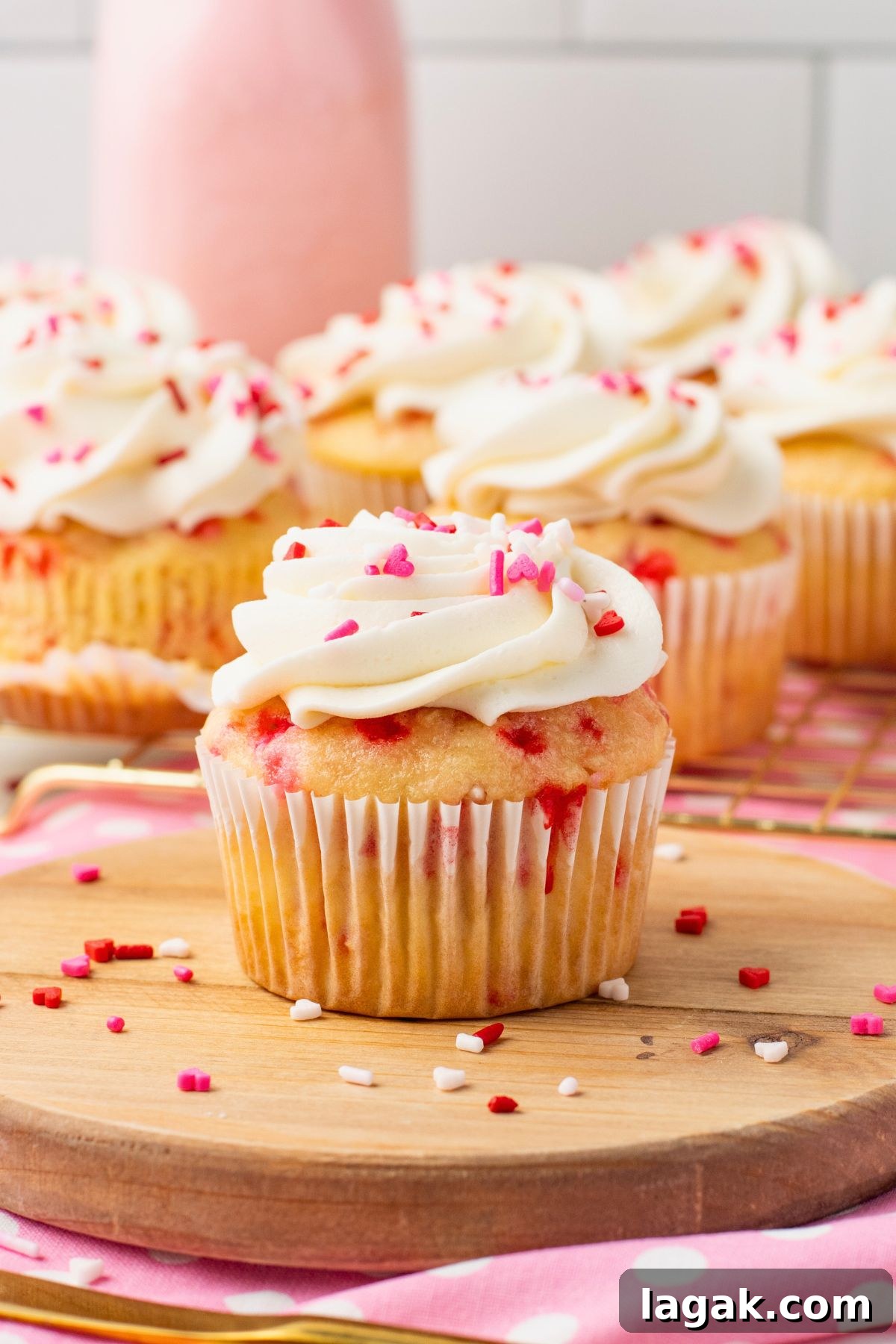 Perfect Pink Cupcake Recipe: Moist, Fluffy Frosting Ideas 2 Vanilla cupcakes filled with pink sprinkles topped with white frosting and pink sprinkles with pink milk in the background.