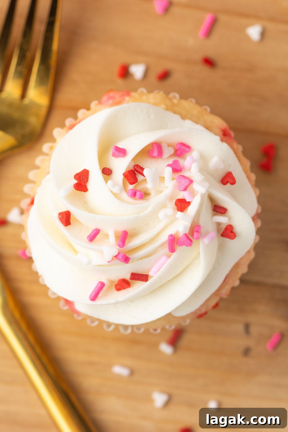 Perfect Pink Cupcake Recipe: Moist, Fluffy Frosting Ideas 11 White cupcakes with white frosting and pink sprinkles on a wooden cutting board.