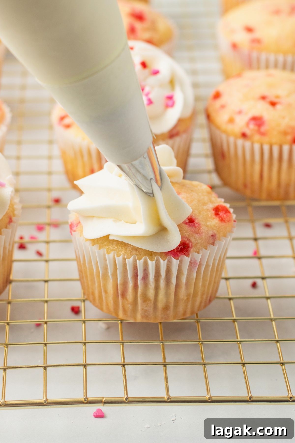 Perfect Pink Cupcake Recipe: Moist, Fluffy Frosting Ideas 9 Pink sprinkled cupcake being frosted with buttercream frosting.