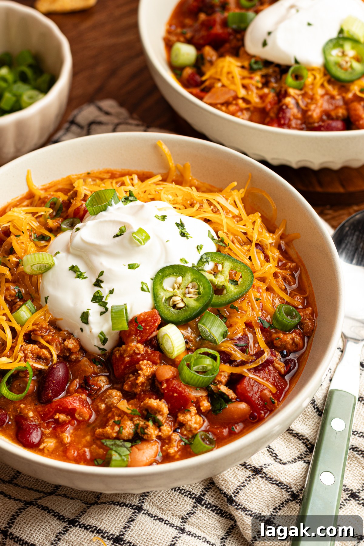 30-Minute High-Protein Turkey Chili Recipe 2 A serving bowl filled with 30 minute turkey chili that's high in protein topped with shredded cheese, sour cream, jalapeños and green onion