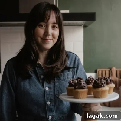 Moist Chocolate Cupcakes with Cream Cheese Frosting Recipe 16 Ella from Alpine Ella is holding a cake stand with cupcakes on it.
