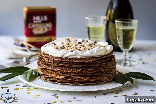 Double-Chocolate-Hazelnut-Crepe-Cake Double-Chocolate-Hazelnut-Crepe-Cake on white platter with champagne glasses, bottle and coffee can in background.