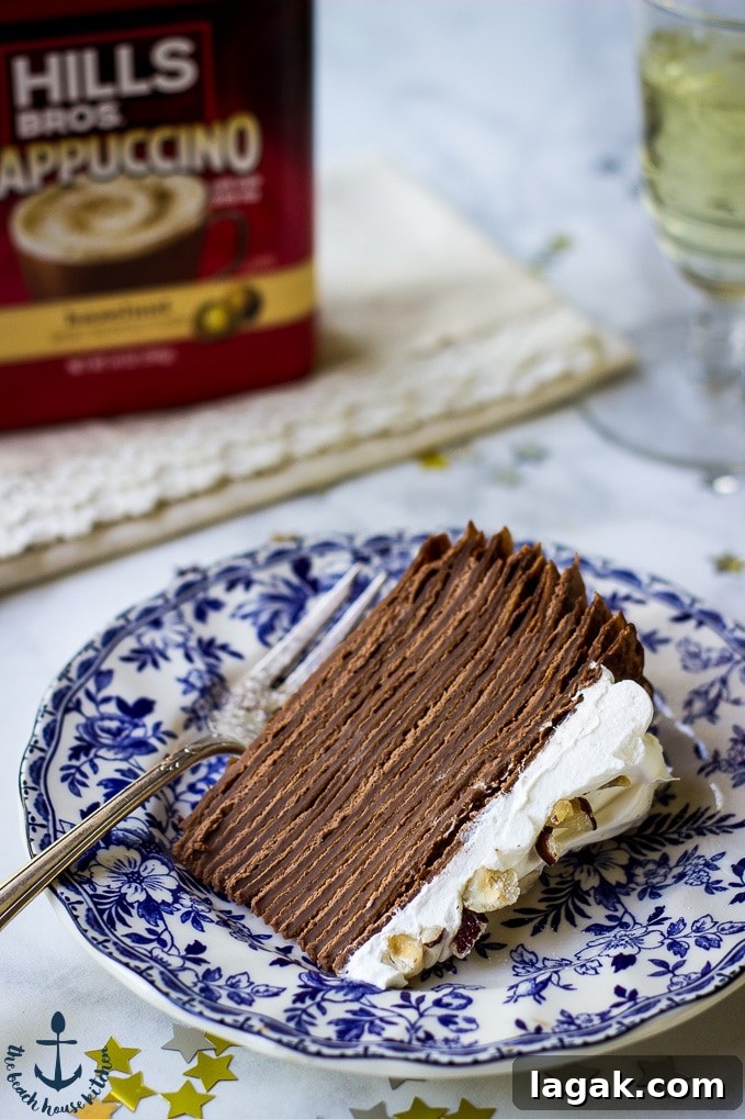 Double-Chocolate-Hazelnut-Crepe Cake Slice of Double Chocolate Hazelnut Crepe Cake on a blue and white plate with coffee container in the background.
